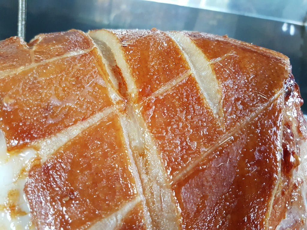 Close-up of scored golden crackling on a whole roast hog