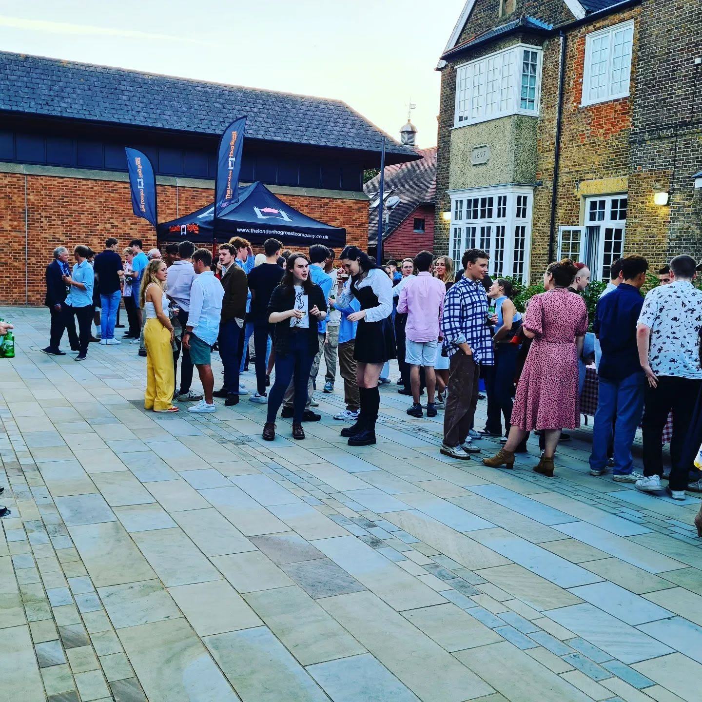 Guests queueing at the hog roast gazebo at an evening event