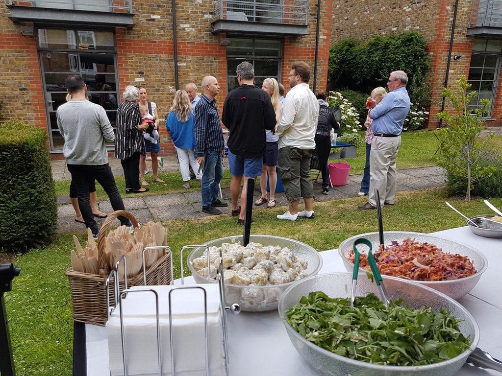 Guests at a small family hog roast party with bowls of homemade salads
