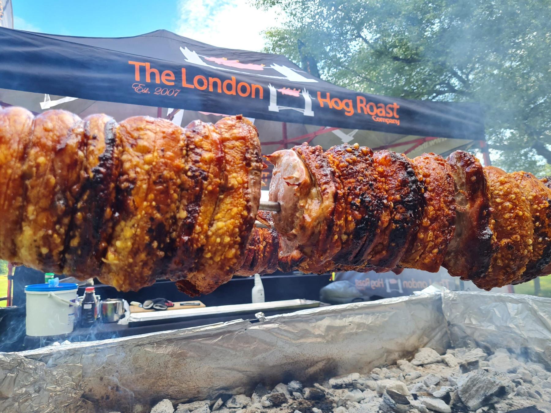 Pork loins with crackling turning on the spit under The London Hog Roast Company gazebo