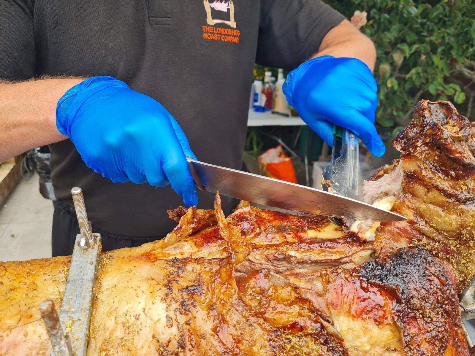 Chef carving charcoal-roasted lamb on the spit