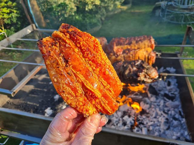 Crackling held up over the coals
