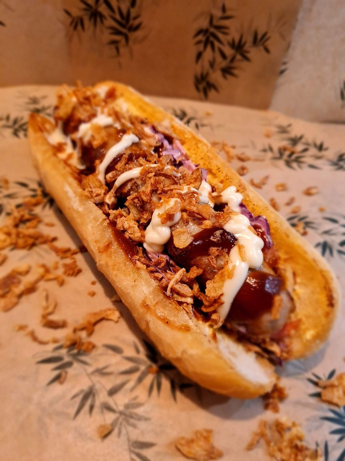 Footlong pork sausage roll topped with crispy onions